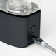 Close-up of black DaVinci EQ base showing side button and braided USB-C charging cable connected