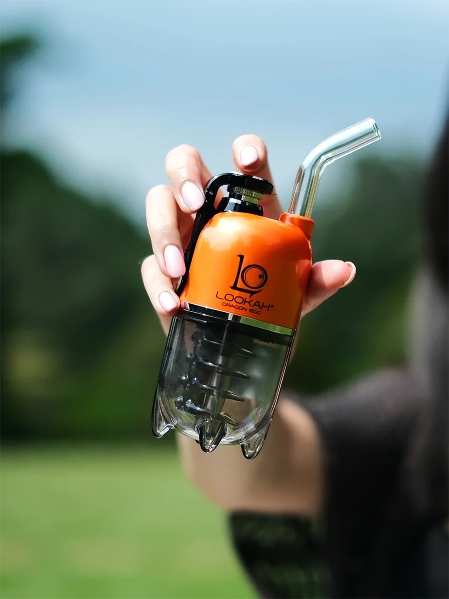 Lookah Dragon Egg handheld e-rig in orange with percolator chamber and angled glass mouthpiece held outdoors