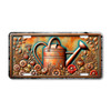 Rustic watering can license plate featuring embossed-look copper watering can surrounded by flowers and leaves in warm bronze and teal tones.