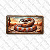 Copper rattlesnake license plate featuring coiled snake with vivid scales in a desert canyon with cactus, rustic embossed-look artwork on aluminum.