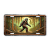 Bigfoot license plate featuring stone relief-style Sasquatch artwork walking through a forest scene printed on aluminum.