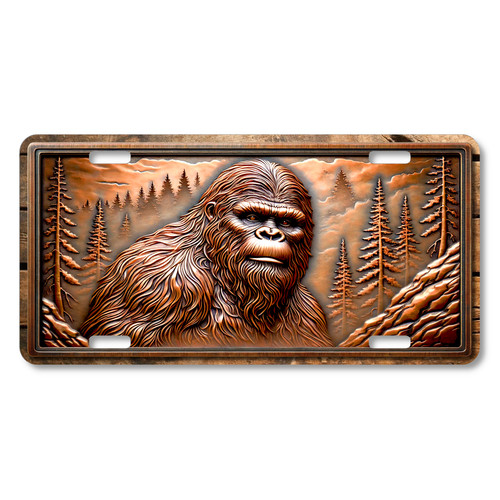 Bigfoot woodland portrait license plate featuring a close-up Sasquatch face surrounded by pine trees, printed on aluminum.