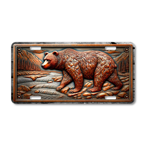 Grizzly Bear license plate featuring rustic mountain stream scene with rocky terrain, pine forest, and bronze tones in embossed-look artwork on aluminum.