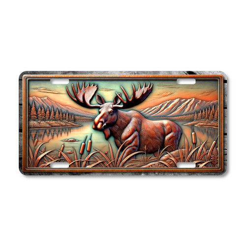Moose license plate featuring a tranquil lakeside mountain scene in bronze and copper tones with embossed-look artwork on aluminum.