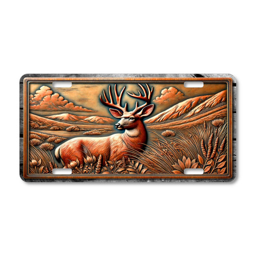 License plate featuring a mule deer resting in tall meadow grasses with mountains and clouds in the background.