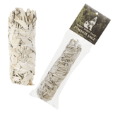 A bundle of dried white sage leaves tightly bound with white string. The bundle is shown twice: once uncovered, revealing the textured, silvery-grey leaves, and once inside its clear plastic retail packaging. The packaging features a dark header card labeled "Wolf Spirit Sage" with an illustration of a howling wolf against a forest background.