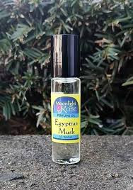 Small glass bottle of Moonlight Rose Egyptian Musk body oil with a black cap, set against green foliage.