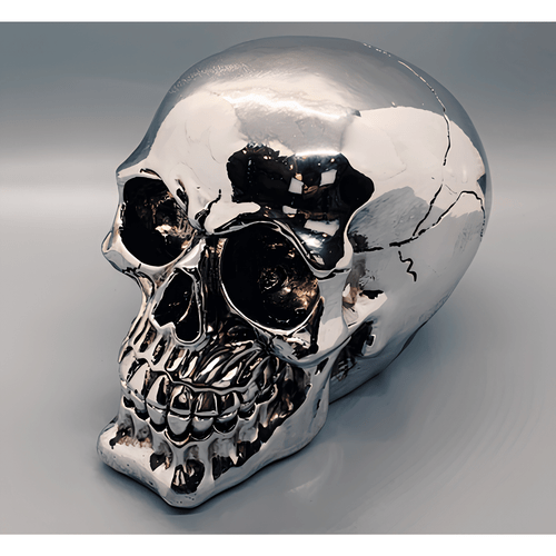 Shiny silver skull made of cold-cast resin, reflecting light with detailed features including eye sockets and carved teeth, positioned against a light gray background.