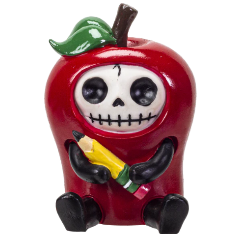 Red apple-shaped figurine with a skull face holding a yellow pencil, featuring black limbs and a green leaf on top.