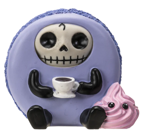 Adorable lavender macaroon figurine with a skull face holding a cup of coffee and sitting next to a pink swirl treat.
