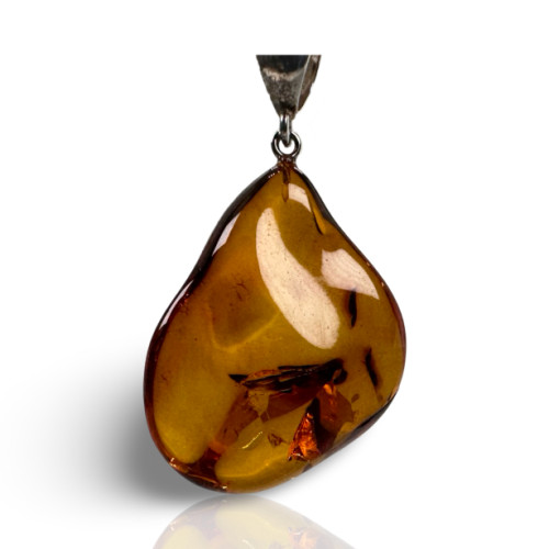 Polished teardrop-shaped natural amber necklace pendant with a sterling silver bail, showcasing rich honey-golden tones.