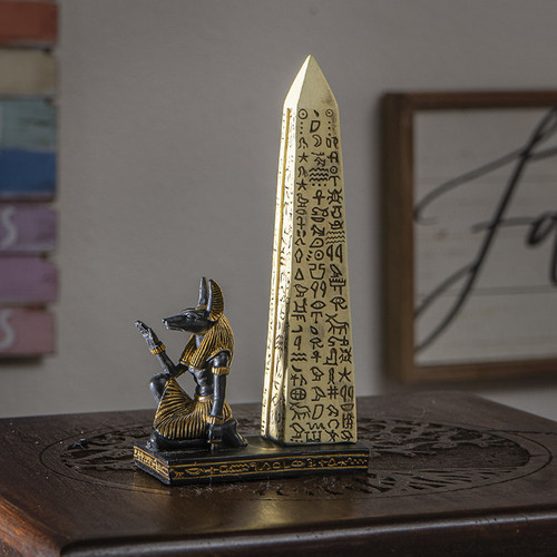 Decorative Egyptian Anubis statue and obelisk incense burner showcased in a home office or living room setting.