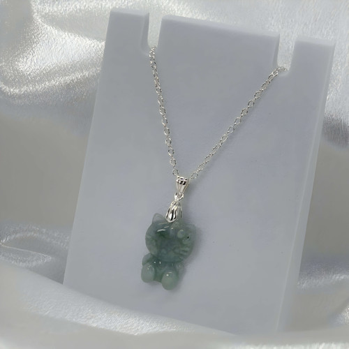Hello Kitty jade necklace with green carved jade pendant on a delicate silver chain displayed on a white jewelry stand.