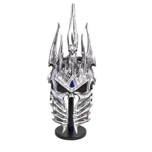 The silver-grey, skull-like Lich King's Helm of Domination from World of Warcraft, featuring a blue gem between the eyebrows and sharp spikes, rests on a black display stand against a white background. The silver-grey, skull-like Lich King's Helm of Domination from World of Warcraft, featuring a blue gem between the eyebrows and sharp spikes, rests on a black display stand against a white background.