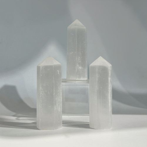 Three translucent white selenite crystal towers with polished, faceted sides and pointed tops