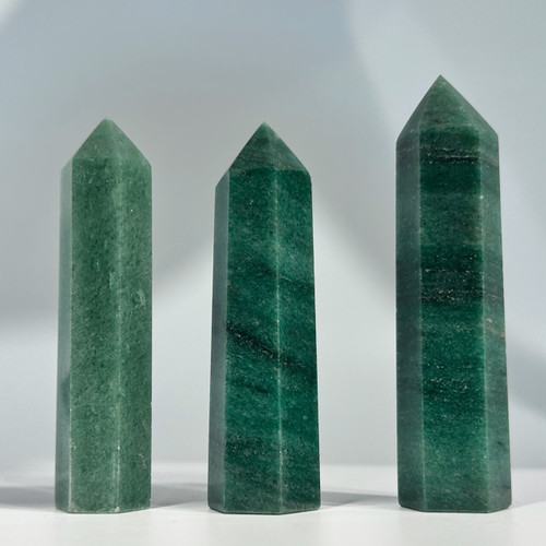 Three dark green aventurine crystal towers, each with a polished, faceted surface and a pointed top Three dark green aventurine crystal towers, each with a polished, faceted surface and a pointed top