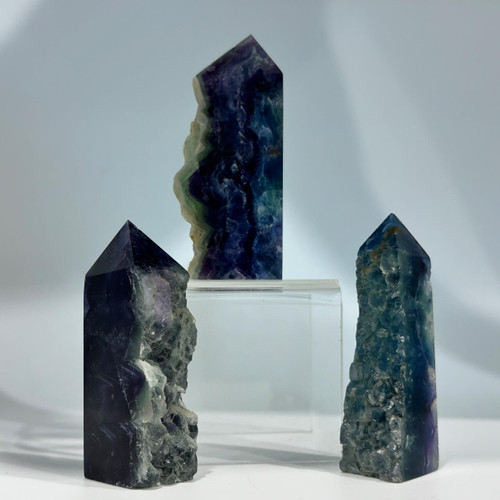 Three partially polished, purple-blue fluorite crystal points showcasing their rough and smooth textures Three partially polished, purple-blue fluorite crystal points showcasing their rough and smooth textures