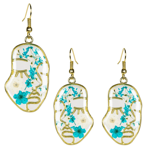 A collage of three abstract, face-shaped dangle earrings featuring real white and turquoise-blue dried flowers preserved in clear resin. The gold-tone wire frame outlines a minimalist profile of a sleeping face with closed eyes and long lashes.