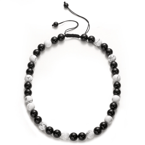 A circular view of an adjustable 12mm beaded gemstone necklace featuring alternating smooth, polished black obsidian beads and white marbled howlite beads
