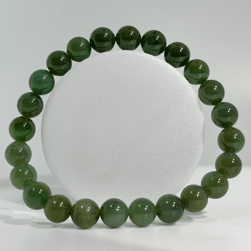 Polished green Jade gemstone bracelet with round natural stone beads laid flat in a loop on a clean white background.