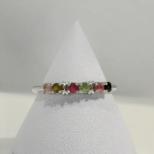 Multicolor Tourmaline eternity ring featuring pink, green, blue, and purple gemstones set in a delicate band on a white jewelry stand.