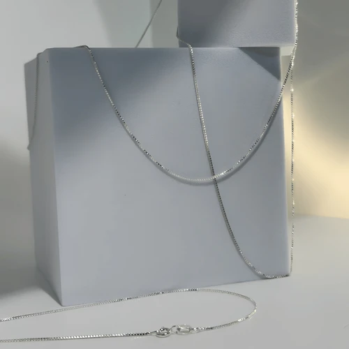 Sterling silver chain necklace displayed on a white jewelry bust with the clasp visible, showcasing its simple and versatile design.