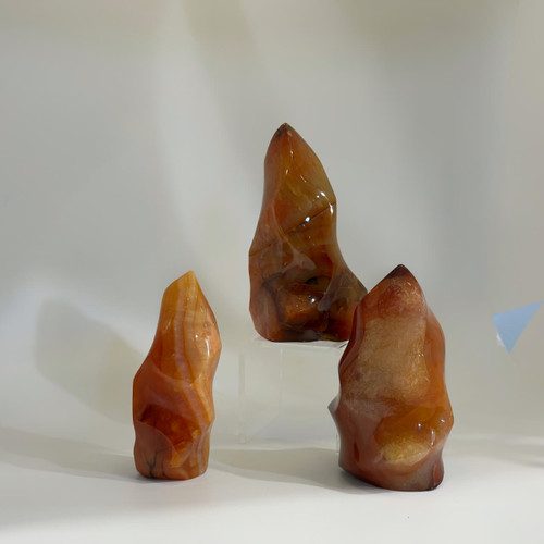 Orange and red Carnelian crystals, flame-shaped and polished, arranged in a group.