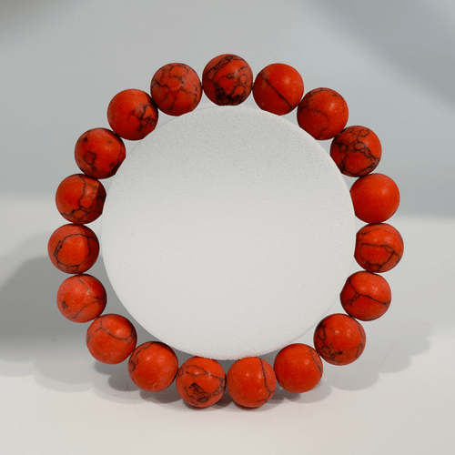 Bracelet made of smooth, round, 10mm reddish-orange dyed howlite gemstone beads with dark veining.