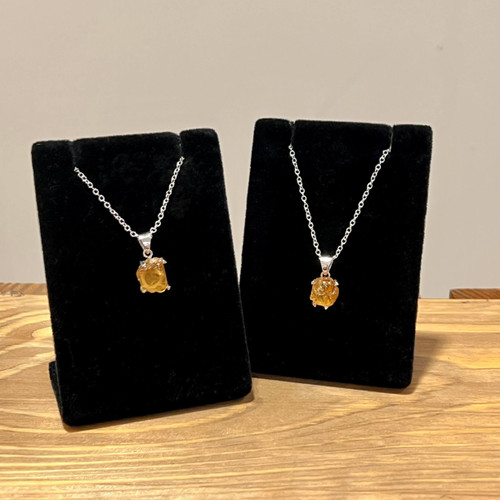 Two rough citrine necklaces on black velvet stands, featuring silver chains and golden-yellow citrine pendants.