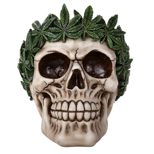 Decorative cream-colored skull made of cold-cast resin, adorned with a wreath of vibrant green cannabis leaves around its crown.