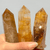 Trio of Golden Healer crystal towers for healing, featuring clear quartz infused with deep gold-to-ochre mineral layers. Trio of Golden Healer crystal towers for healing, featuring clear quartz infused with deep gold-to-ochre mineral layers.