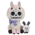 Whimsical resin figurine of a larger alpaca creature with a skull face, adorned with a lavender bow, next to a smaller sheep-like figure with curved horns.
