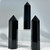 Three polished black obsidian crystal points with smooth, glossy, jet-black appearance and reflective surfaces.