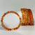 Carnelian Gemstone Bracelet featuring smooth, polished orange and amber gemstone beads, displayed beside stacked bracelets with varying bead sizes on a clean white background.