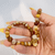 Hand holding a Crazy Lace Agate Gemstone Bracelet made with genuine polished agate beads in warm natural tones.