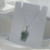 Hello Kitty jade necklace with green carved jade pendant on a delicate silver chain displayed on a white jewelry stand.