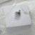 Angled view of a Hello Kitty jade necklace featuring a green carved jade pendant and sterling silver chain on a white display box.