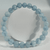 Aquamarine gemstone bracelet with smooth, light blue glossy round beads displayed on a white foam stand.