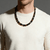 A man wearing a Triple Protection Necklace with large 12mm gemstone beads. The bold contrast of the dark obsidian, shimmering tiger eye, and reflective hematite beads creates a grounded, masculine look against a simple white t-shirt.