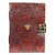 A dark brown leather journal, intricately embossed with a large evil eye design at its center, featuring a striking tiger's eye gemstone as the iris. The journal has decorative swirling patterns around the eye and a metal clasp lock system on the right side.