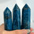 A hand holds three vibrant blue apatite crystal points, believed to enhance clarity and motivation, showing their natural striations.