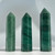 Three dark green aventurine crystal towers, each with a polished, faceted surface and a pointed top