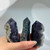 Three partially polished fluorite crystal points displaying a mix of purple and white, blue and green, and dark purple and gray, each with a unique raw, unpolished texture on one side.