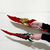 The Kamish's Wrath Duo Dagger Set from Solo Leveling. The top dagger has a vibrant red blade with a gold, dragon-scale crossguard, while the bottom dagger has a red and black blade with a black, jagged crossguard. Both are being held against a white brick wall.