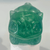 A gemstone carving of the Pokémon Bulbasaur crafted from sea-foam green fluorite. The stone is semi-translucent with a smooth, polished finish, showing subtle internal crystalline structures and white wispy inclusions. The carving captures Bulbasaur’s rounded body, pointed ears, large triangular eyes, and the seedling bulb resting on its back.