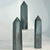 Three tall, hexagonal Hematite crystal towers standing vertically. The polished gemstones feature a metallic, gunmetal gray finish with subtle sparkling inclusions. One tower is elevated on a clear acrylic block against a clean, white background, emphasizing their sleek, geometric design.