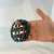 A close-up view of a person’s open palm holding a cluster of three looped blue kyanite beaded stretch bracelets, demonstrating their scale and texture. The polished gemstone beads flash with rich, layered bands of oceanic blue and metallic silver streak variations, catching the light to reveal the natural crystalline depth of the stones against a bright white backdrop.