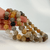 Hand holding multiple Garden Quartz gemstone bead bracelets with polished natural crystal beads in warm neutral shades, showcasing the bracelets' color variation and craftsmanship.