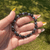 Tourmaline and Hematite gemstone bead bracelet held outdoors, showcasing polished natural stone beads in sunlight.