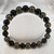 Tourmaline & Pyrite Gemstone Bracelet with polished black tourmaline and pyrite beads displayed in a circular arrangement on a white background.